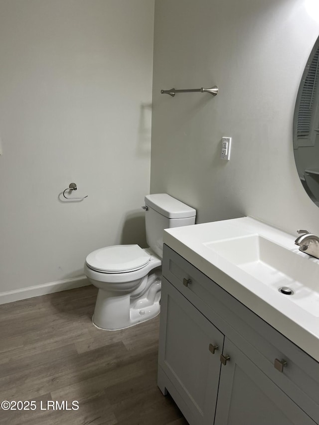 bathroom featuring wood-type flooring, toilet, and vanity