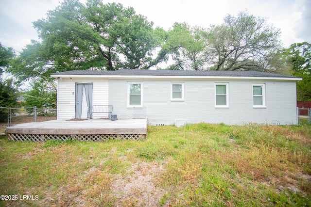 back of property with brick siding, a wooden deck, and fence