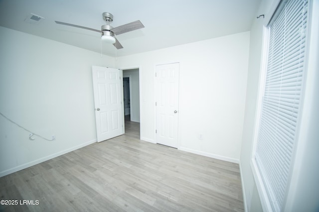 unfurnished bedroom with baseboards, ceiling fan, wood finished floors, and visible vents