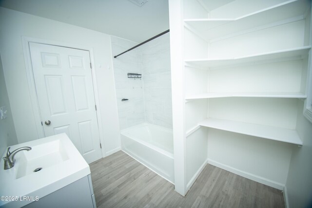 full bathroom with a sink, baseboards, bathtub / shower combination, and wood finished floors