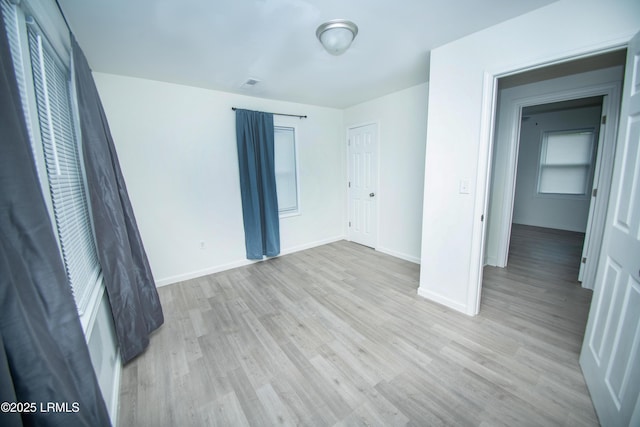 unfurnished bedroom featuring light wood-type flooring, baseboards, and visible vents