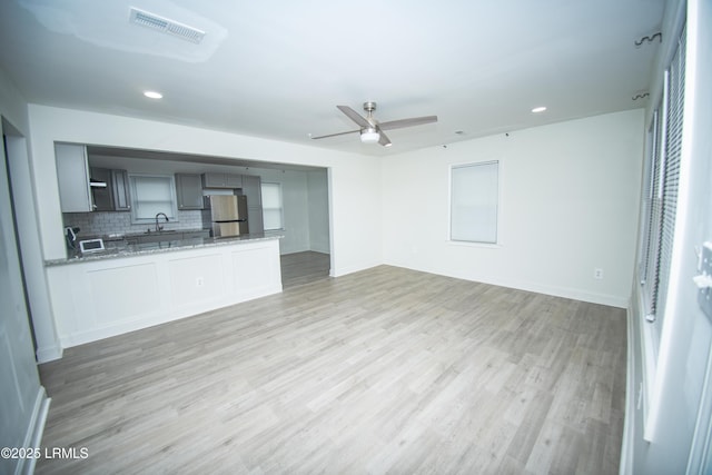 unfurnished living room featuring a sink, light wood-style flooring, a ceiling fan, recessed lighting, and visible vents