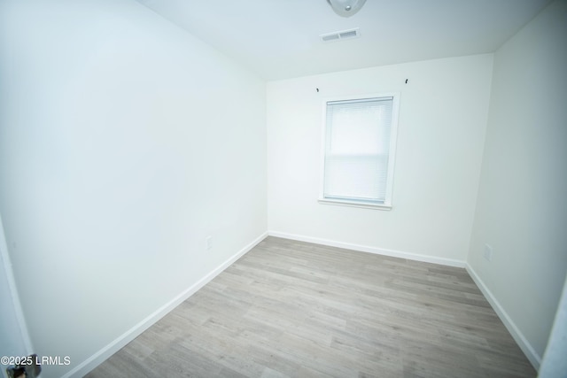 unfurnished room with baseboards, wood finished floors, and visible vents