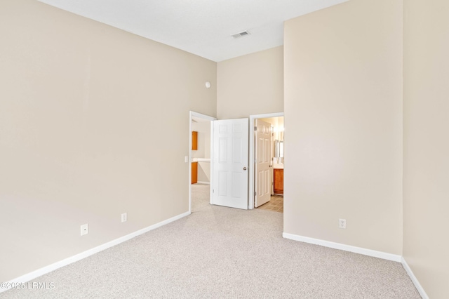 897 Fording Island Rd Unit 301, Bluffton, SC 29910 - unfurnished bedroom featuring light colored carpet, baseboards, connected bathroom, and a towering ceiling