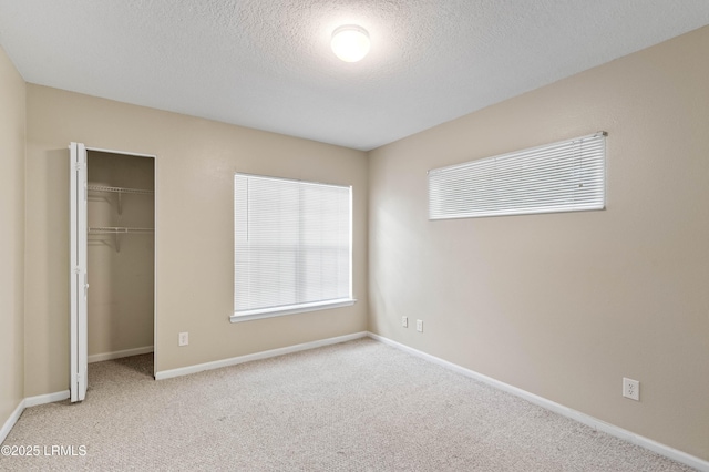 897 Fording Island Rd Unit 301, Bluffton, SC 29910 - unfurnished bedroom featuring carpet, a closet, a textured ceiling, baseboards, and a spacious closet