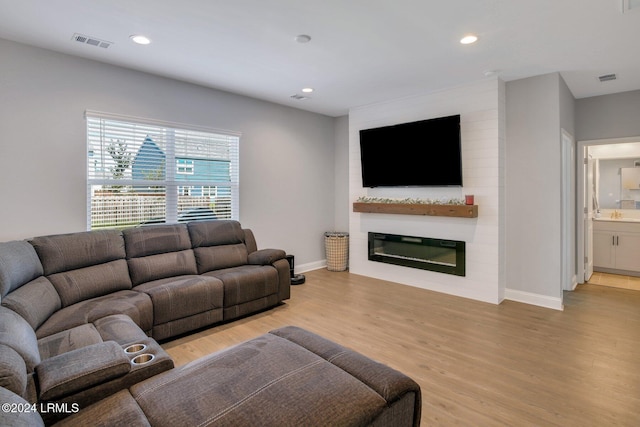 living room with a large fireplace and light wood-type flooring