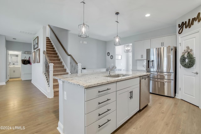 kitchen with white cabinetry, appliances with stainless steel finishes, sink, and a center island with sink