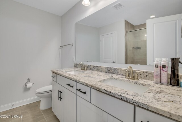 bathroom with a shower with door, vanity, tile patterned floors, and toilet