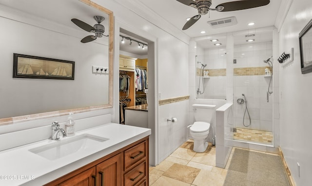 full bath with visible vents, toilet, a ceiling fan, a tile shower, and vanity