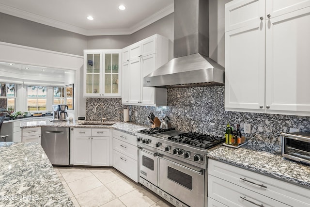 kitchen with ornamental molding, wall chimney exhaust hood, appliances with stainless steel finishes, and a sink