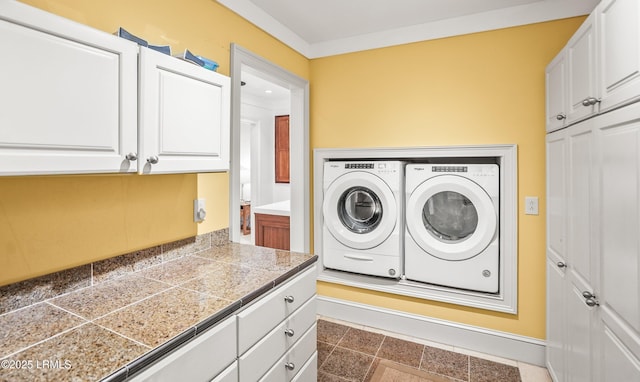 clothes washing area featuring washing machine and dryer, cabinet space, and baseboards