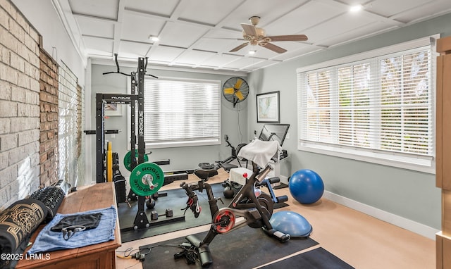 exercise area with brick wall, a ceiling fan, and baseboards