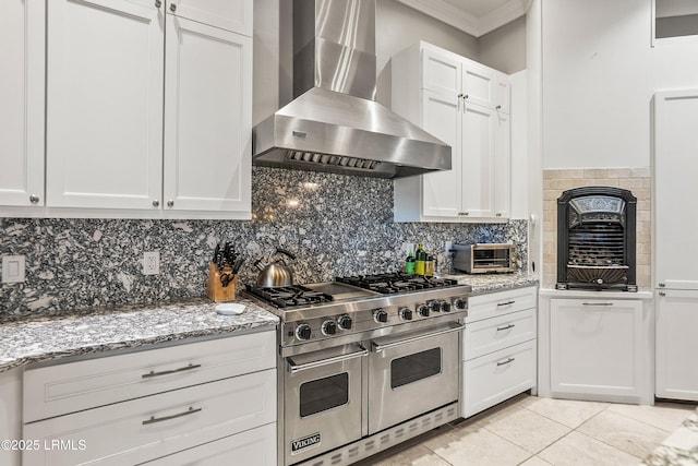 kitchen with range with two ovens, white cabinets, ornamental molding, wall chimney range hood, and tasteful backsplash