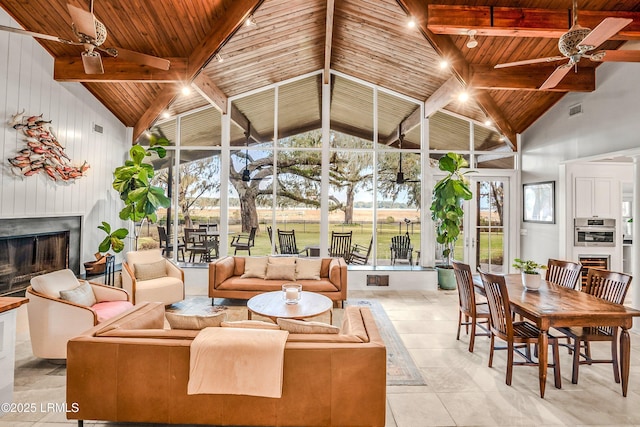 sunroom / solarium featuring vaulted ceiling with beams, wood ceiling, a fireplace, and ceiling fan