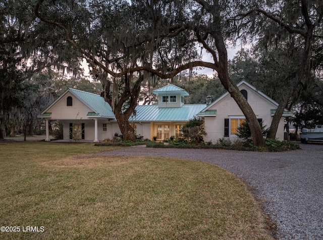 view of front of home featuring stucco siding, a front yard, a standing seam roof, metal roof, and driveway