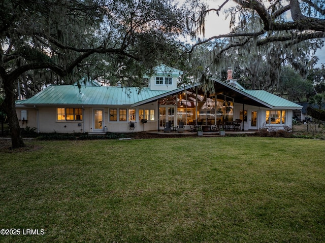 back of property with metal roof and a yard