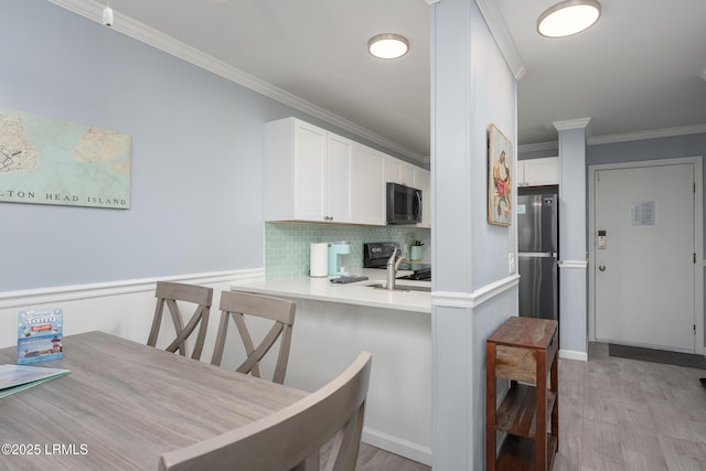 663 William Hilton Pkwy Unit 2126, Hilton Head Island, SC 29928 - kitchen with black microwave, freestanding refrigerator, crown molding, stove, and a breakfast bar area