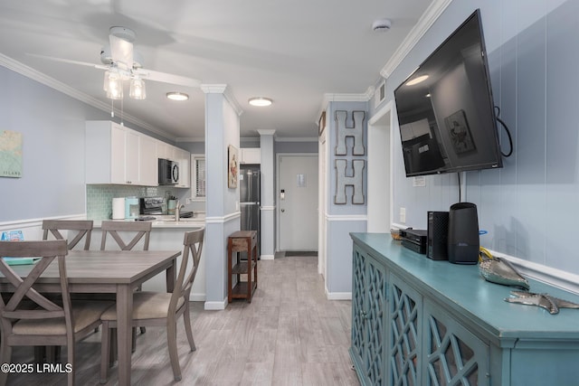 663 William Hilton Pkwy Unit 2126, Hilton Head Island, SC 29928 - kitchen featuring black microwave, ornamental molding, backsplash, white cabinetry, and light wood finished floors