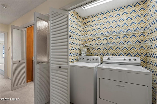 laundry area with laundry area, a textured ceiling, washer and dryer, and light colored carpet