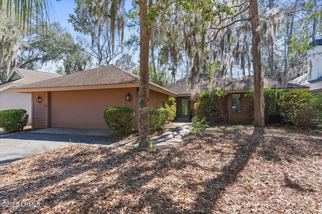 ranch-style home with a garage, driveway, and roof with shingles