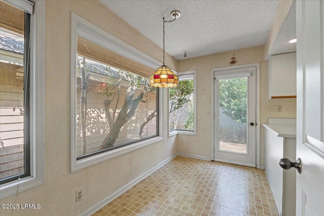 unfurnished dining area with a textured ceiling and baseboards