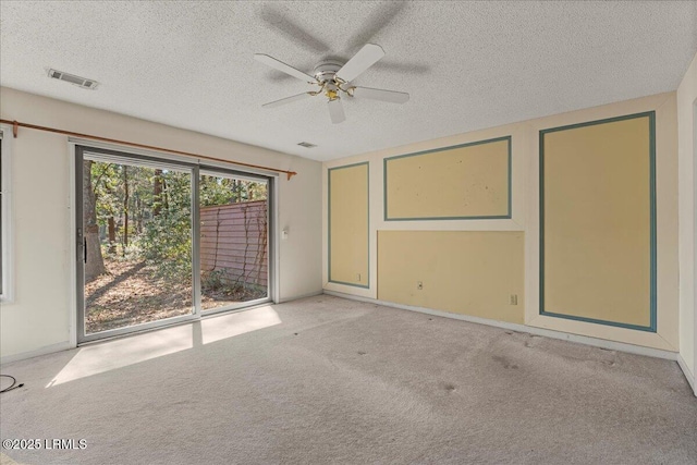 carpeted spare room with a textured ceiling, baseboards, visible vents, and a ceiling fan