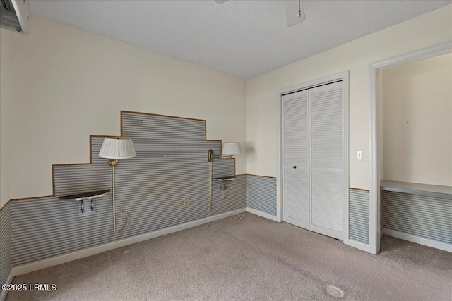 unfurnished bedroom featuring ceiling fan, carpet floors, a closet, and wainscoting