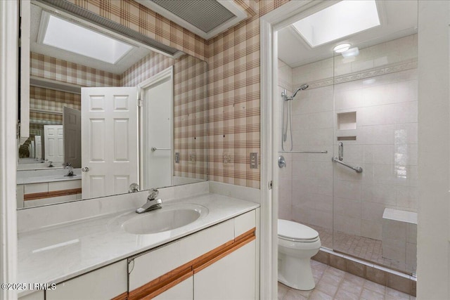 bathroom with toilet, a skylight, vanity, a shower stall, and wallpapered walls