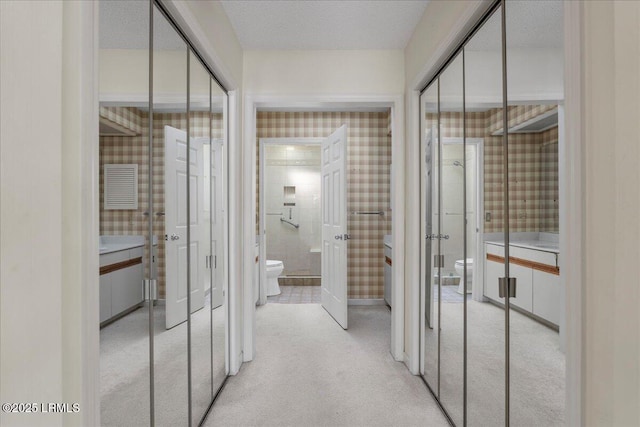 hallway with light carpet and a textured ceiling