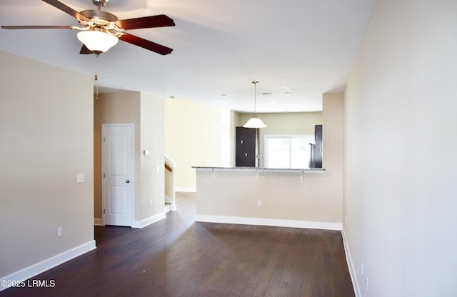 unfurnished living room featuring dark wood-type flooring and ceiling fan