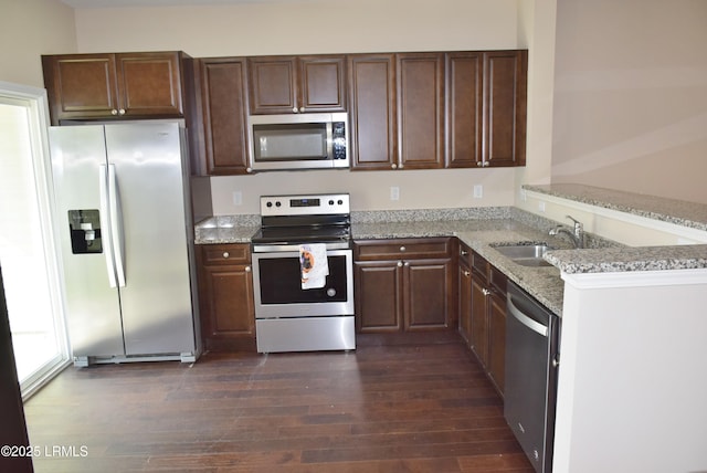 kitchen featuring sink, stainless steel appliances, light stone countertops, dark hardwood / wood-style flooring, and kitchen peninsula