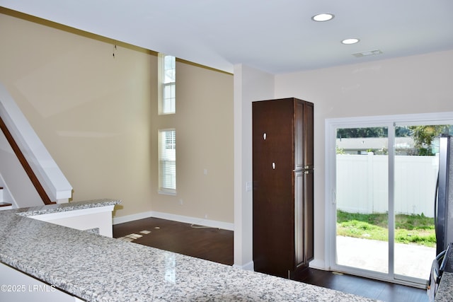 interior space with light stone counters and dark hardwood / wood-style flooring