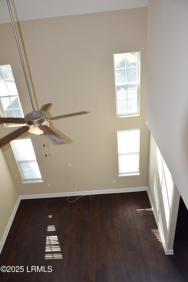 spare room with a high ceiling, dark wood-type flooring, and ceiling fan