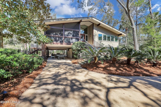 34 W Beach Lagoon Dr, Hilton Head Island, SC 29928 - exterior space featuring a carport, stairway, concrete driveway, and a sunroom