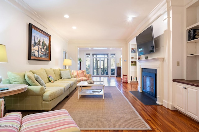 living room featuring built in shelves, dark hardwood / wood-style flooring, and crown molding