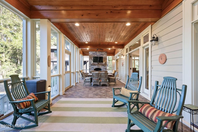 sunroom with wood ceiling and an outdoor stone fireplace