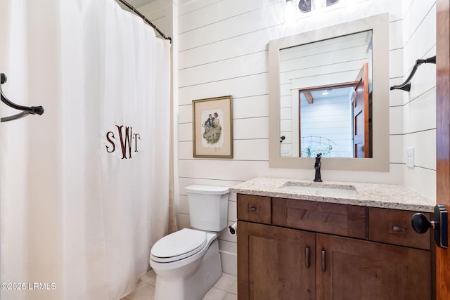 bathroom with vanity, tile patterned floors, toilet, and wood walls