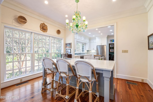 kitchen featuring white cabinetry, hanging light fixtures, stainless steel appliances, tasteful backsplash, and light hardwood / wood-style floors