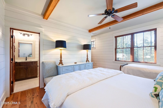 bedroom with wooden walls, beamed ceiling, sink, hardwood / wood-style flooring, and ceiling fan