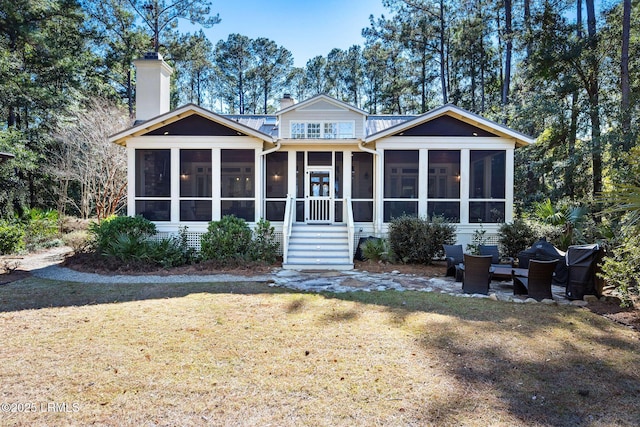 back of house featuring a sunroom and a lawn