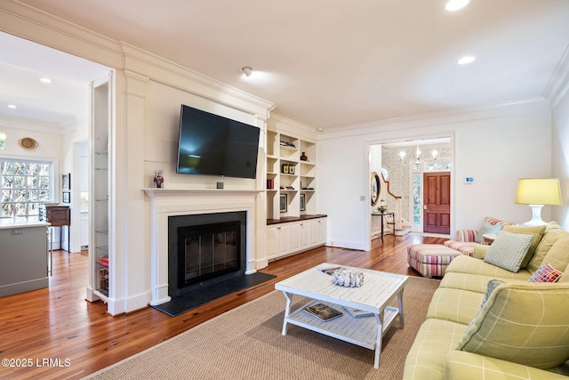 living room with an inviting chandelier, hardwood / wood-style floors, and ornamental molding