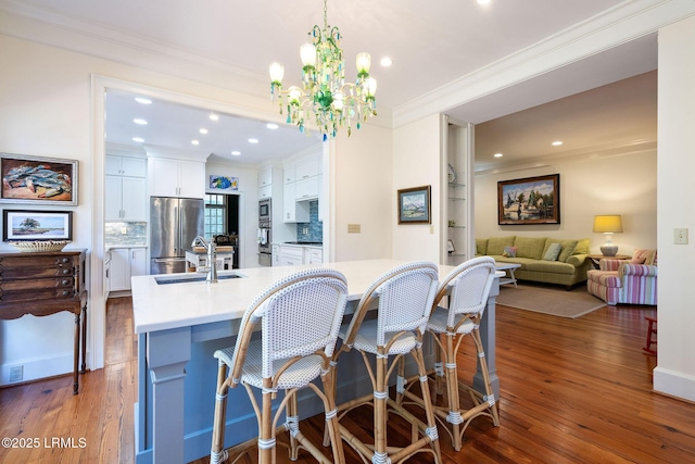 kitchen with pendant lighting, white cabinetry, sink, a kitchen island with sink, and stainless steel appliances