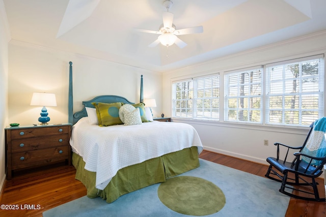 bedroom featuring a raised ceiling, dark wood-type flooring, ceiling fan, and multiple windows