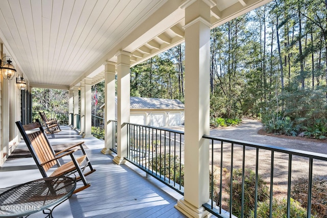 deck with a porch, an outdoor structure, and a garage