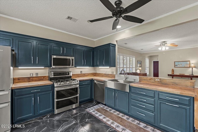 101 Redtail Dr, Bluffton, SC 29909 - kitchen featuring appliances with stainless steel finishes, butcher block countertops, blue cabinets, a ceiling fan, and a textured ceiling