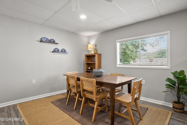 dining space with dark hardwood / wood-style floors and a drop ceiling