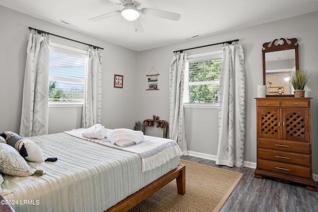 bedroom with multiple windows, dark hardwood / wood-style floors, and ceiling fan