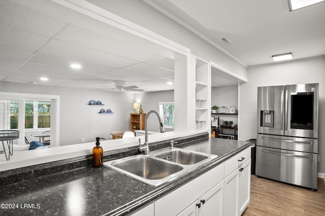 kitchen featuring stainless steel refrigerator with ice dispenser, sink, light wood-type flooring, ceiling fan, and white cabinets