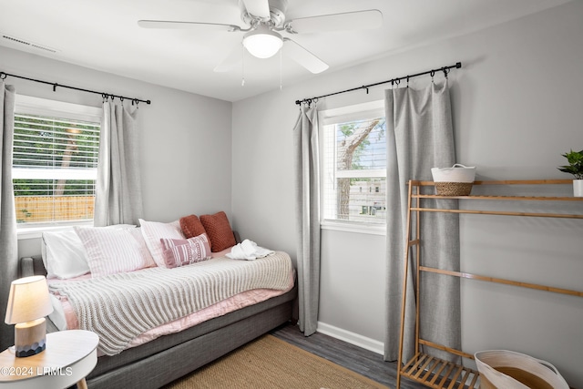 bedroom with multiple windows, dark hardwood / wood-style floors, and ceiling fan