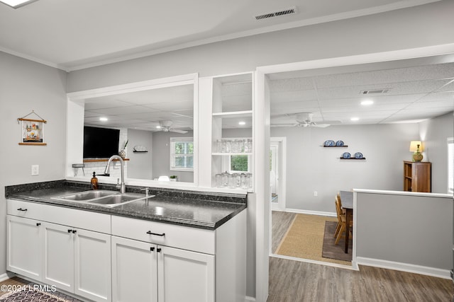 kitchen featuring sink, hardwood / wood-style flooring, ceiling fan, white cabinetry, and a drop ceiling